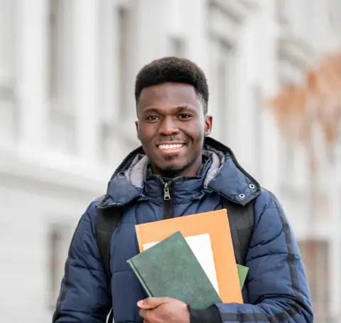 Smiling student holding notebooks